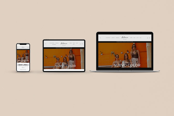 Un Iphone, un Ipad y una laptop mostrando cada uno el inicio de la página web de Antonia Bikinis. Los tres dispositivos están uno al lado del otro sobre un fondo color entero beige. 