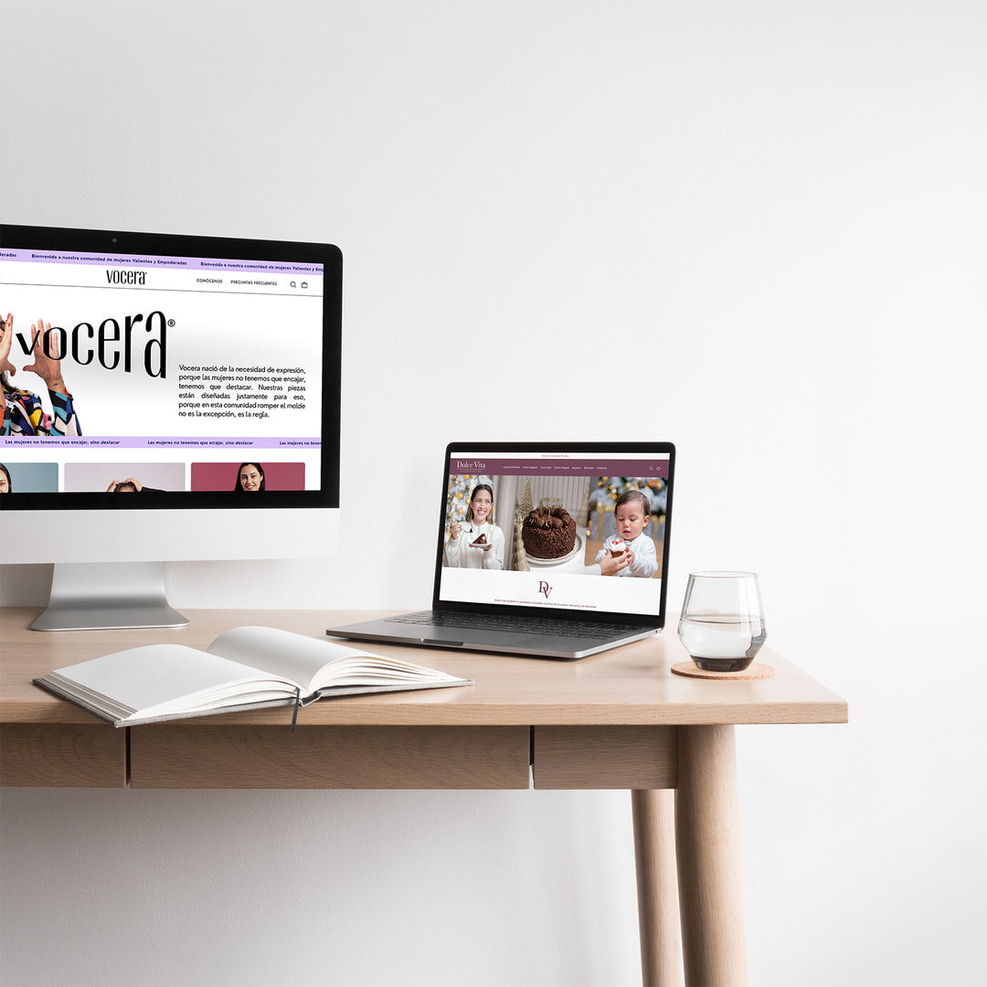 Una computadora y una laptop abierta sobre una mesa. En la pantalla de la computadora se ve el inicio de la web de la marca Vocera y en la laptop se ve abierto el inicio de la web del negocio Dolce Vita.