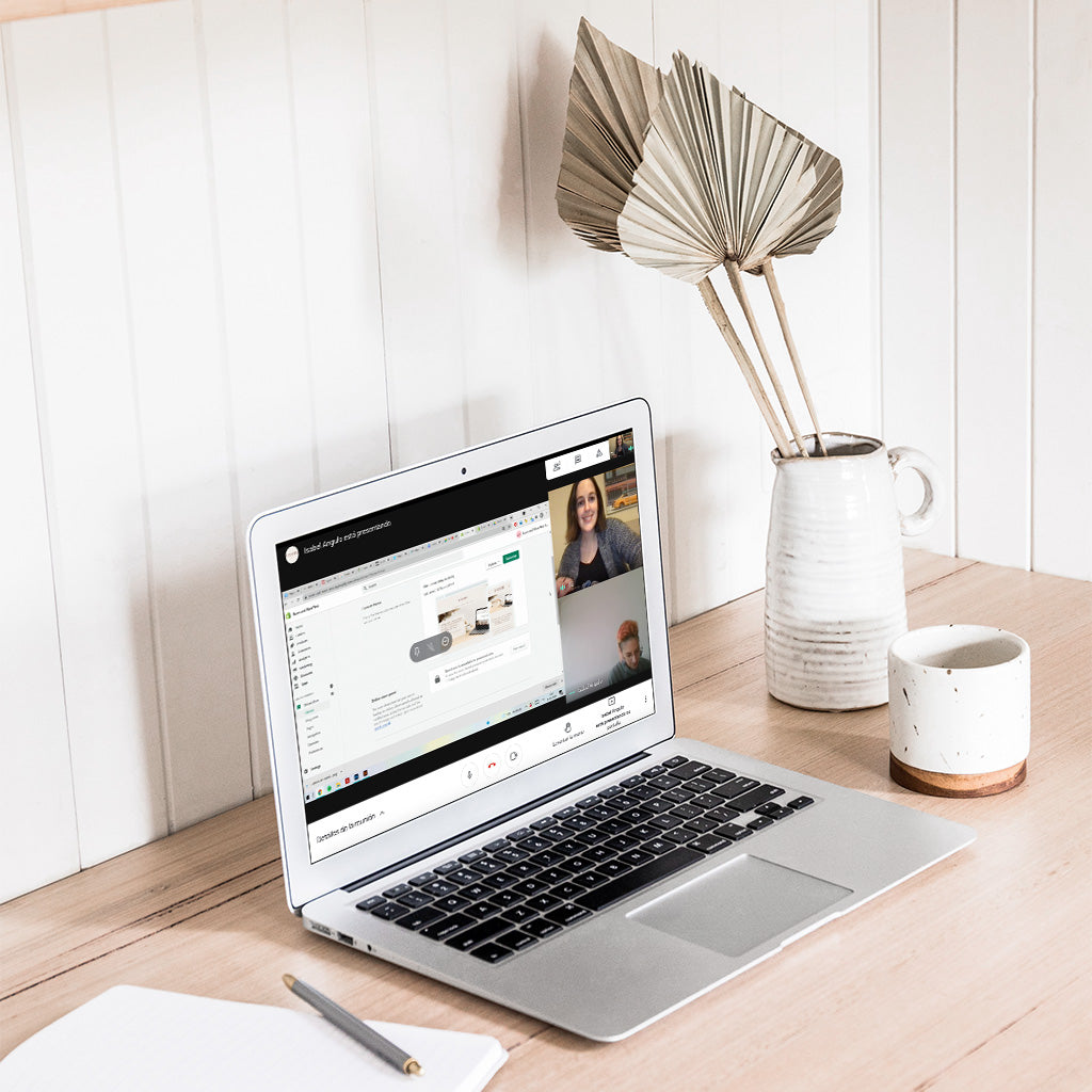Una laptop abierto sobre una mesa. En su pantalla se encuentra abierta una videollamada.