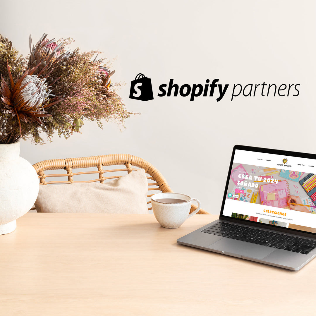 Una laptop abierta sobre una mesa. En la pantalla se muestra la web de Happy Handra Encima de la imagen está sobreimpreso el logo de Shopify Partners.