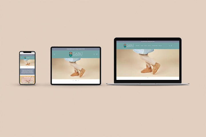 Un Iphone, un Ipad y una laptop mostrando cada uno el inicio de la página web de Gabu Babies and Kids. Los tres dispositivos están uno al lado del otro sobre un fondo color entero beige. 