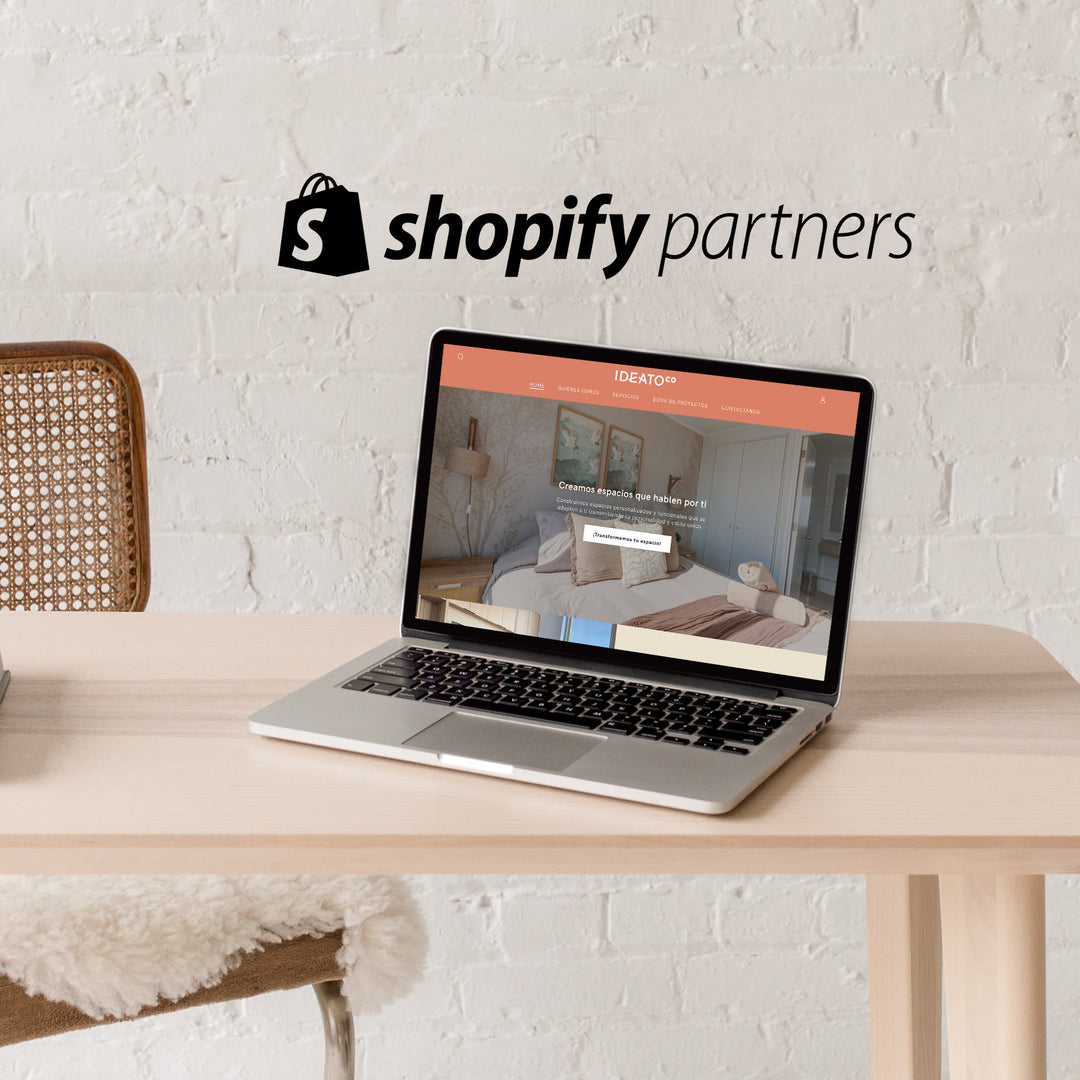 Una laptop abierta sobre una mesa. En la pantalla se muestra la web de Ideato co.. Encima de la imagen está sobreimpreso el logo de Shopify Partners.